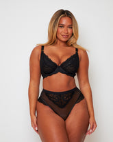 Model wearing the Tutti Rouge Harlow Fuller Bust Bra and High Waist Brief Set in Midnight Black with delicate floral lace, sheer mesh and supportive fuller bust fit.