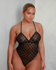 Front view of the Tutti Boudoir Kaylee Bodysuit in Onyx Black, featuring sheer monogram mesh, a plunging triangle neckline, high-cut legs and a sleek, sculpting silhouette designed to flatter every curve.