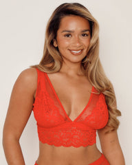 Woman wearing a red lace bralette against a plain background