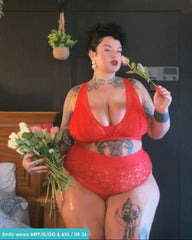 Customer wearing the Hallie Bralette and Brief Set in Chilli Pepper Red from Tutti Rouge, posing indoors while holding flowers. The set features floral lace detailing and a supportive fuller-bust fit.