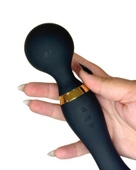 Black handheld device with gold accent held by a hand on a white background