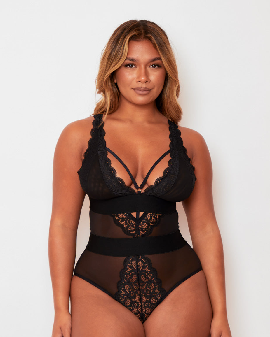 Three-quarter view of the Alicia Bodysuit in Black by Tutti Rouge, highlighting the plunging lace cups, sheer mesh body, and flattering panelled design.