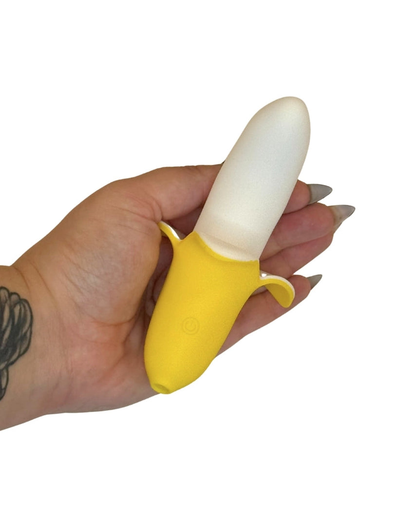 Hand holding a yellow and white banana toy against a white background