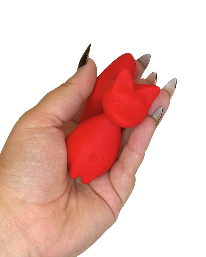 Red cat-shaped object held in a hand with a white background