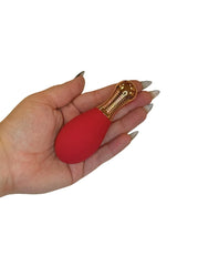 Hand holding a red object with gold accents on a white background