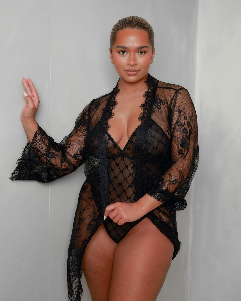 The Tutti Boudoir Kaylee Bodysuit in Onyx Black styled with the matching sheer lace robe, combining delicate lace, lightweight mesh and the signature monogram bodysuit for an effortlessly luxurious lingerie look.